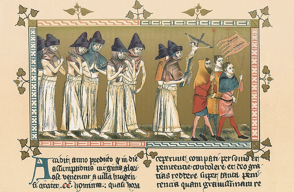 A 1349 manuscript illustration showing a procession of flagellants walking single file through a town, stripped to the waist, swinging knotted scourges over their shoulders to whip their backs, while townspeople watch from the side; the brick buildings of a Flemish town form the backdrop
